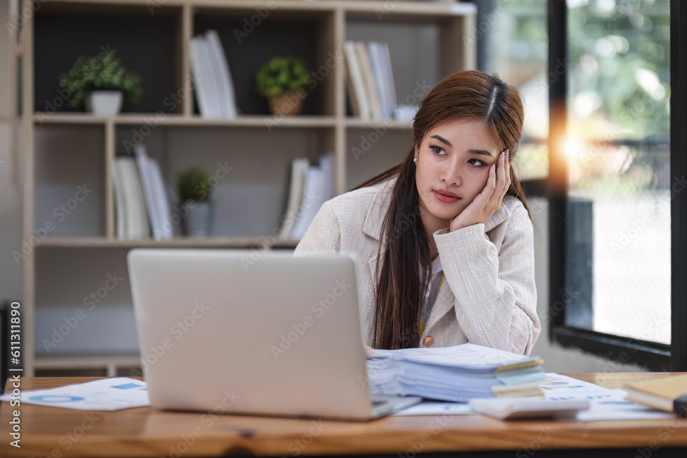 Portrait of a serious asian businesswoman thinking and concentrating typing on laptop at co-working spaces. Black screen laptop for graphic montage. Woman laptop working concept Portrait of a serious asian businesswoman thinking and concentrating typing on laptop at co-working spaces. Black screen laptop for graphic montage. Woman laptop working concept