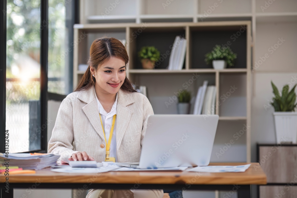 Asian Businesswoman Using laptop computer and working at office with calculator document on desk, doing planning analyzing the financial report, business plan investment, finance analysis concept. Asian Businesswoman Using laptop computer and working at office with calculator document on desk, doing planning analyzing the financial report, business plan investment, finance analysis concept.