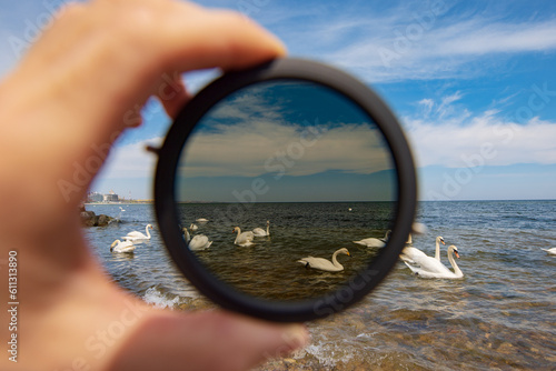 Fotografi Neutral filter for the camera in the male hand, view on a sea