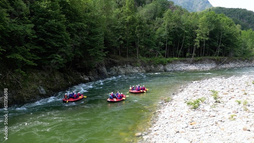 Go rafting on the river with dinghies immersed in the rapids of the stream and the nature of the canyon in Val Sesia Alagna Piedmont Alps mountains - drone view of summer water sport activities 
