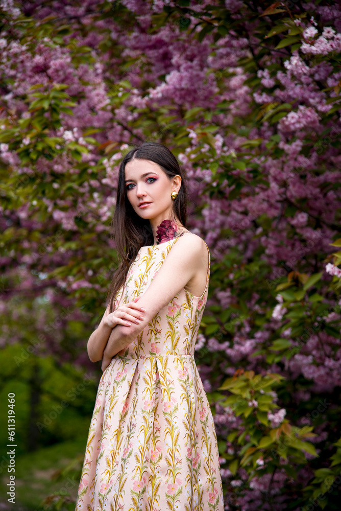 portrait of sensitive beautiful brunette woman with tattoo on her neck in dress in the garden near blossoming sakura flowers portrait of sensitive beautiful brunette woman with tattoo on her neck in dress in the garden near blossoming sakura flowers