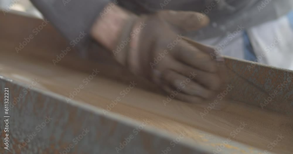 A worker hand uses sandpaper to smooth metal part of construction during the production process A worker hand uses sandpaper to smooth metal part of construction during the production process