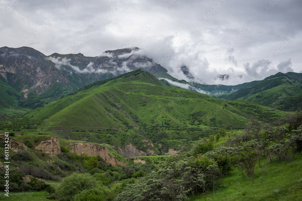 Summer mountain landscape. Amazing view of the valley and lush green pastures in the Caucasus, Georgia. Surrounded by high mountain ranges. Cloudy and rainy day in spring, low storm clouds. Summer mountain landscape. Amazing view of the valley and lush green pastures in the Caucasus, Georgia. Surrounded by high mountain ranges. Cloudy and rainy day in spring, low storm clouds.