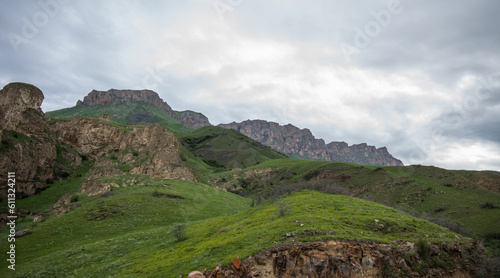 Summer mountain landscape. Amazing view of the valley and lush green pastures in the Caucasus, Georgia. Surrounded by high mountain ranges. Cloudy and rainy day in spring, low storm clouds.