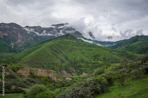 Summer mountain landscape. Amazing view of the valley and lush green pastures in the Caucasus  Georgia. Surrounded by high mountain ranges. Cloudy and rainy day in spring  low storm clouds.