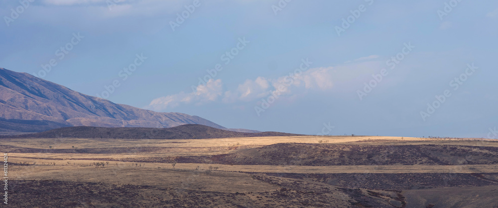 Unusual mountain landscape on a dull autumn day. Remote foothill areas in northern China. Dry grassy fields and hills. Natural background. Exploration of new places, travel to remote locations.