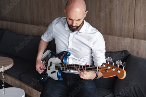 Handsome bald man with beard playing bass guitar. Professional musician