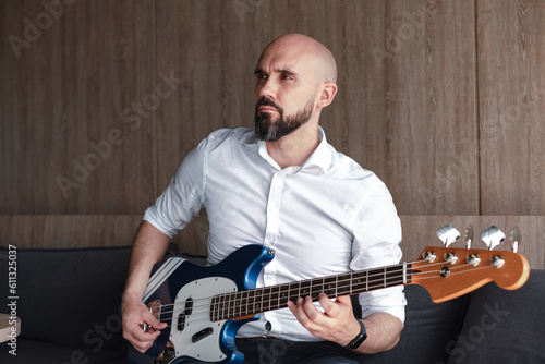 Handsome bald man with beard playing bass guitar. Professional musician