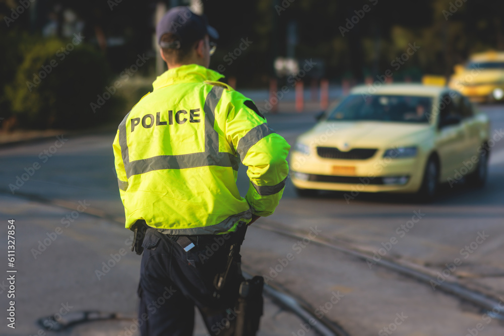 Inspector of traffic police highway patrol regulates the movement of transport in the center of european city, in green yellow vest jacket with a sign Inspector of traffic police highway patrol regulates the movement of transport in the center of european city, in green yellow vest jacket with a sign