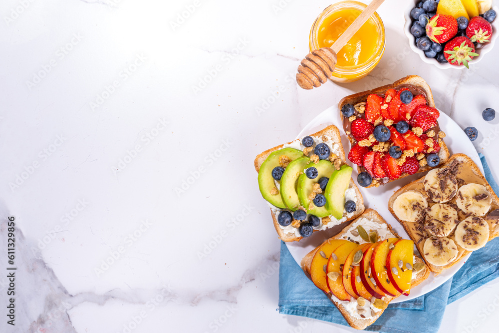 Fruit berry sandwiches. Various toasts with peanut butter, cream cheese, chocolate spread with summer berries and fruits - strawberry, banana, peach, apple, blueberry, Tasty morning lunch food