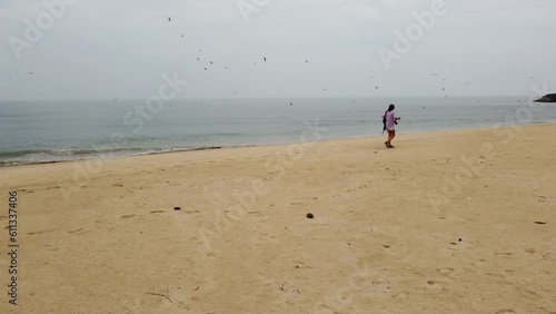 Wallpaper Mural Shooting from a drone - a girl with a backpack walks along an empty beach and seagulls fly over the sea Torontodigital.ca