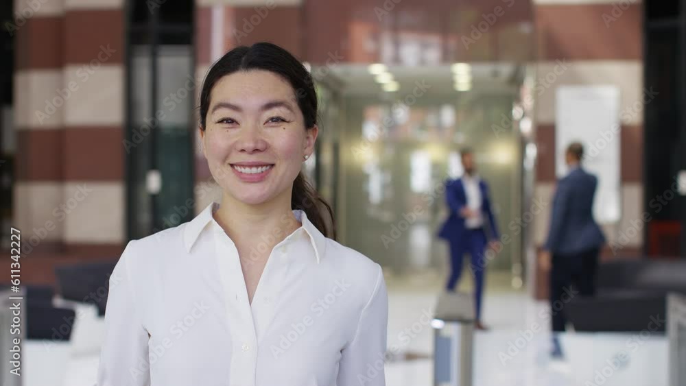 Portrait of attractive Asian female executive smiling to camera in a building lobby Portrait of attractive Asian female executive smiling to camera in a building lobby