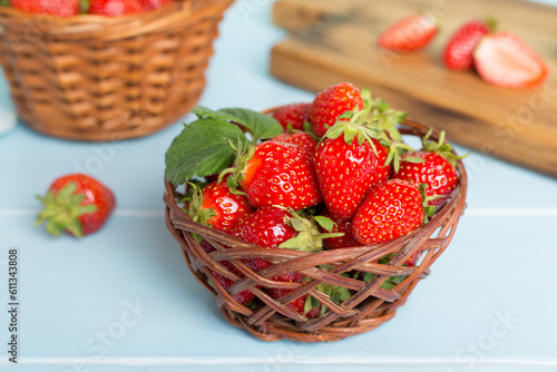 Fresh strawberries in wicker basket on wooden table