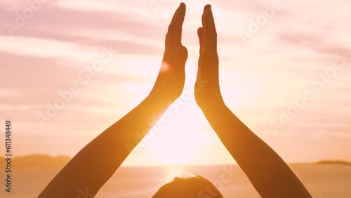 CLOSE UP, LENS FLARE: View of female hands in meditation pose at sunset by sea. She is on a relaxing vacation, practicing yoga in the embrace of stunning Mediterranean seascape on sunny island of Hvar photo