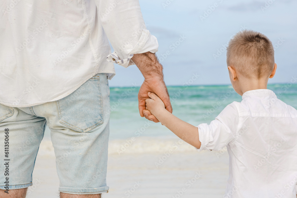 Father and son holding hand in hand. Concept of friendly family Father and son holding hand in hand. Concept of friendly family