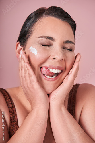Vertical portrait of the happy body positive woman posing with beauty product on her face