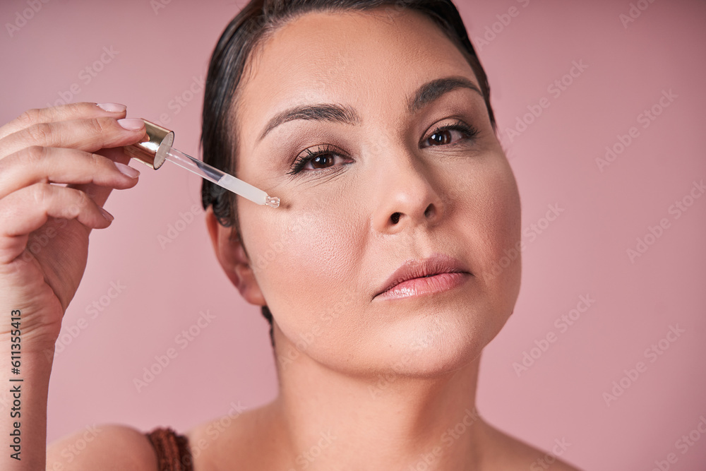 Body positive woman applying serum on face