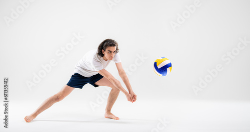 A young volleyball player is training with a ball on a white background. Action, sport, health, team, fitness concept