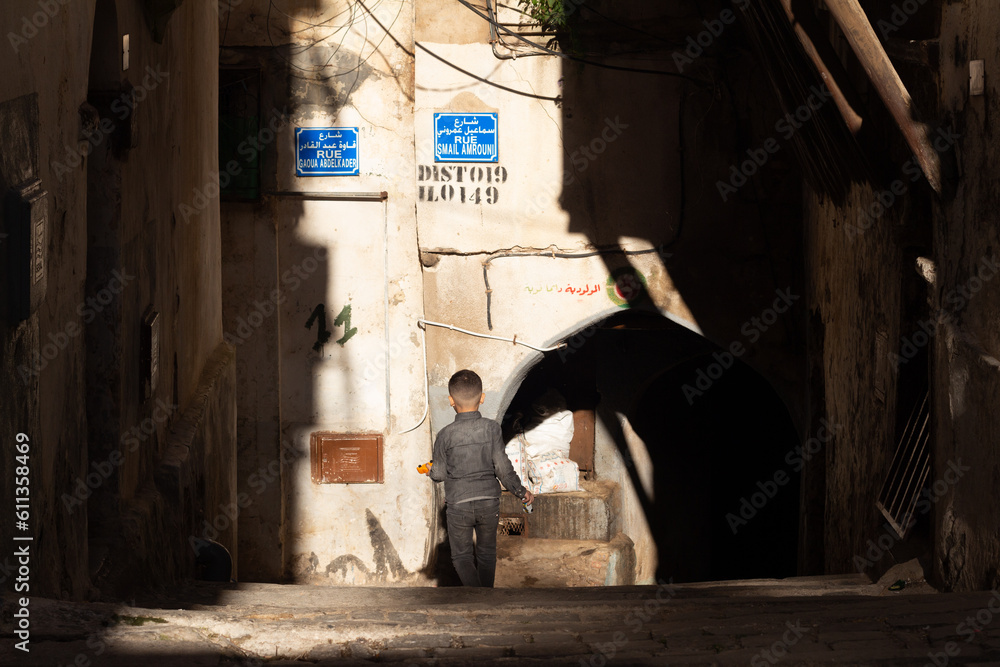 Street scene in the Casbah of Algiers (Alger), Algeria. Young boy walking. Stone stairs and ancient ottoman houses. Chiaroscuro atmosphere.