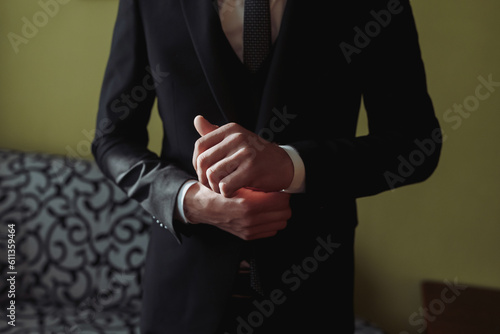 cropped photo of stylish man fixing black jacket. Front view. A stylish watch. Men's style. Fashion. Business