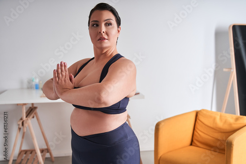 Body positive woman holding hands in prayer gesture and looking away