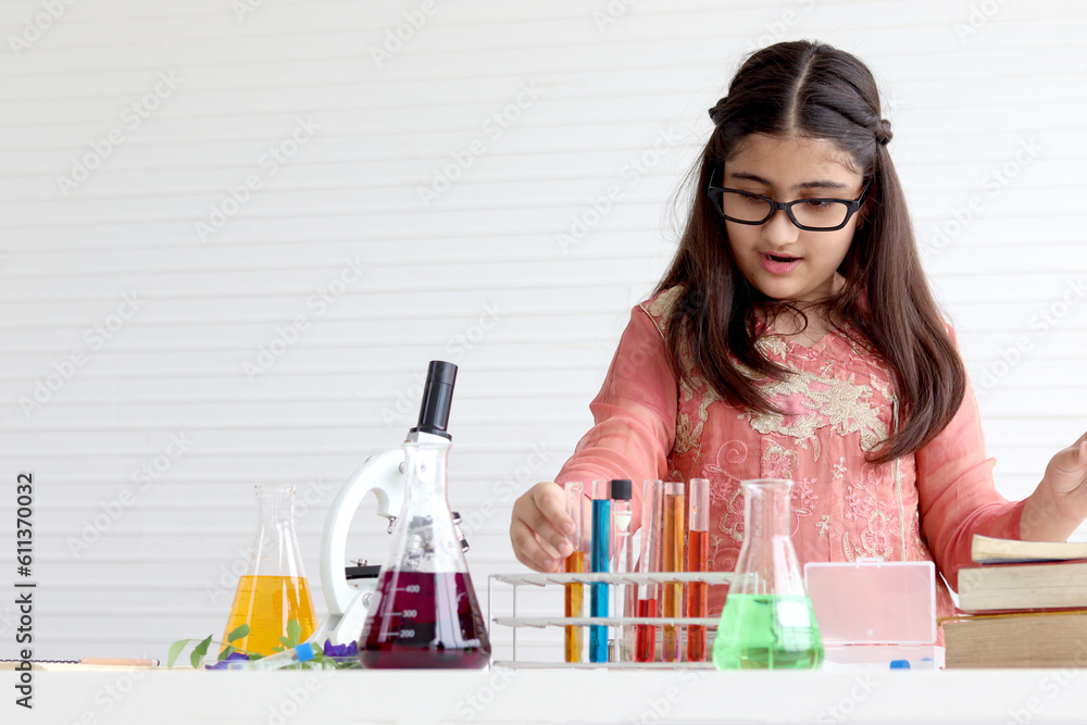 Cute Indian school girl in India traditional dress costume doing science experiments in laboratory, young scientist kid with microscope and lab equipment learning biologics and chemistry in classroom. Cute Indian school girl in India traditional dress costume doing science experiments in laboratory, young scientist kid with microscope and lab equipment learning biologics and chemistry in classroom.