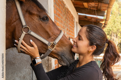 Happy woman hugging horse in stable photo