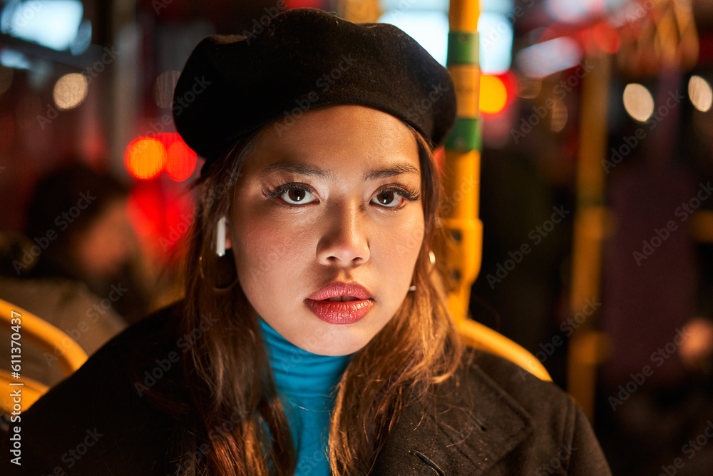 Serious asian woman ride in public transport bus or tram and looking at camera