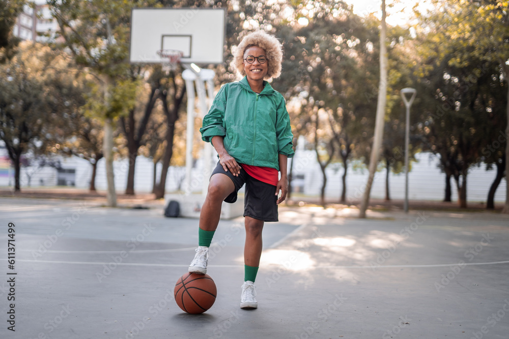 Positive young woman with basketball on court in park Positive young woman with basketball on court in park
