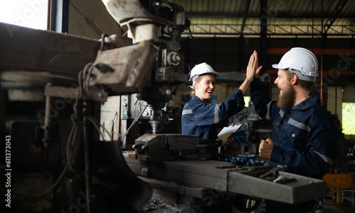 Both of mechanical engineers are checking the working condition of an old machine that has been used for some time. In a factory where natural light shines onto the workplace © Wosunan