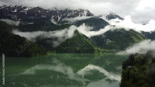 Aerial drone view of lake and green forest in  national park. Clouds laying on mountains. Scenic View of water in a lake with pine trees. Mountain lake  with morning fog photo