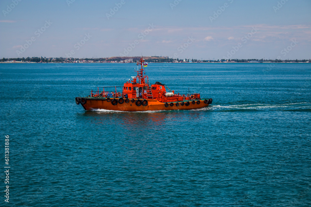 A small red boat sails in the clear blue sea A small red boat sails in the clear blue sea