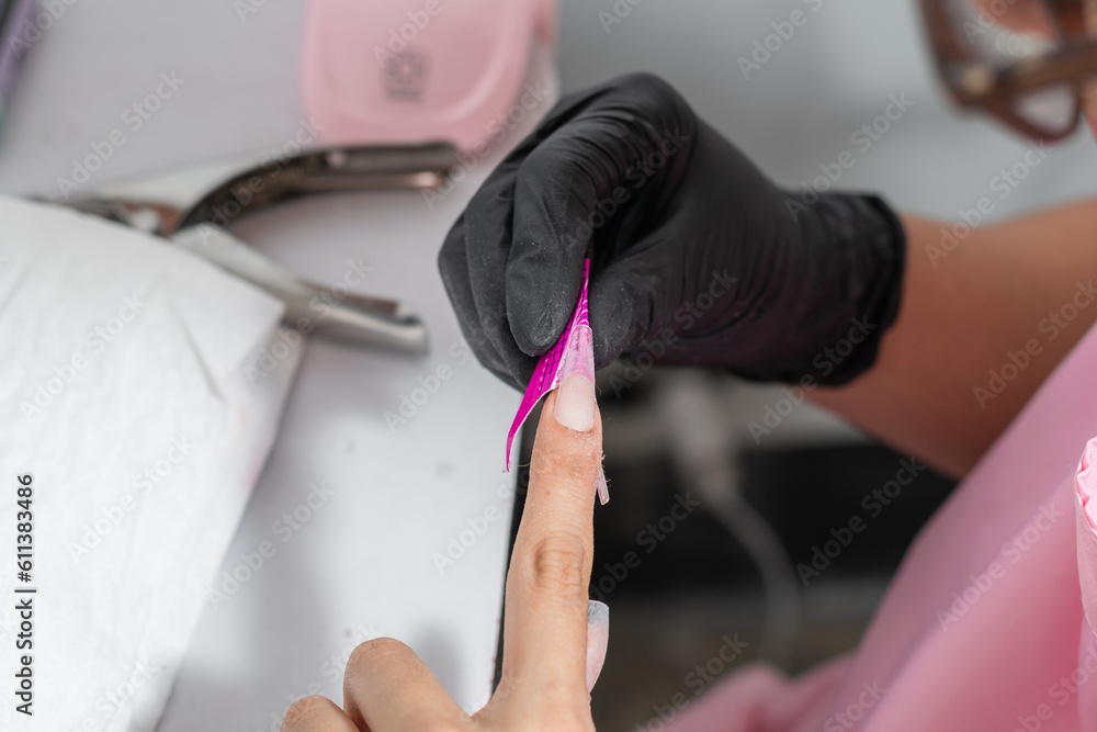 detailed view of the hands of a girl who is measuring her artificial nail to know where to cut it detailed view of the hands of a girl who is measuring her artificial nail to know where to cut it