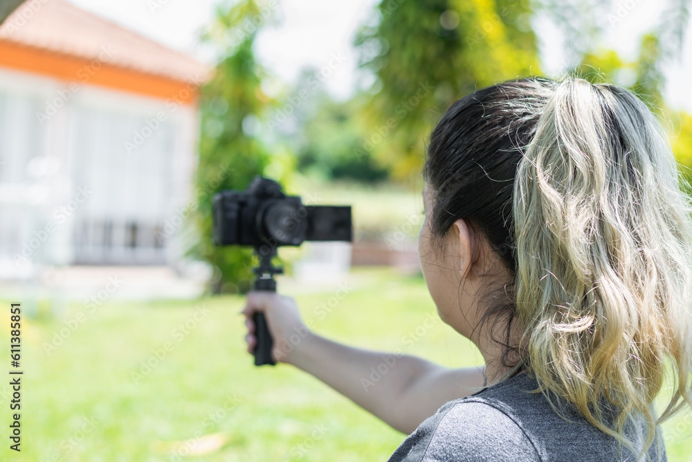 close-up of the back of the head of a blogger girl recording herself with a camera in her hand