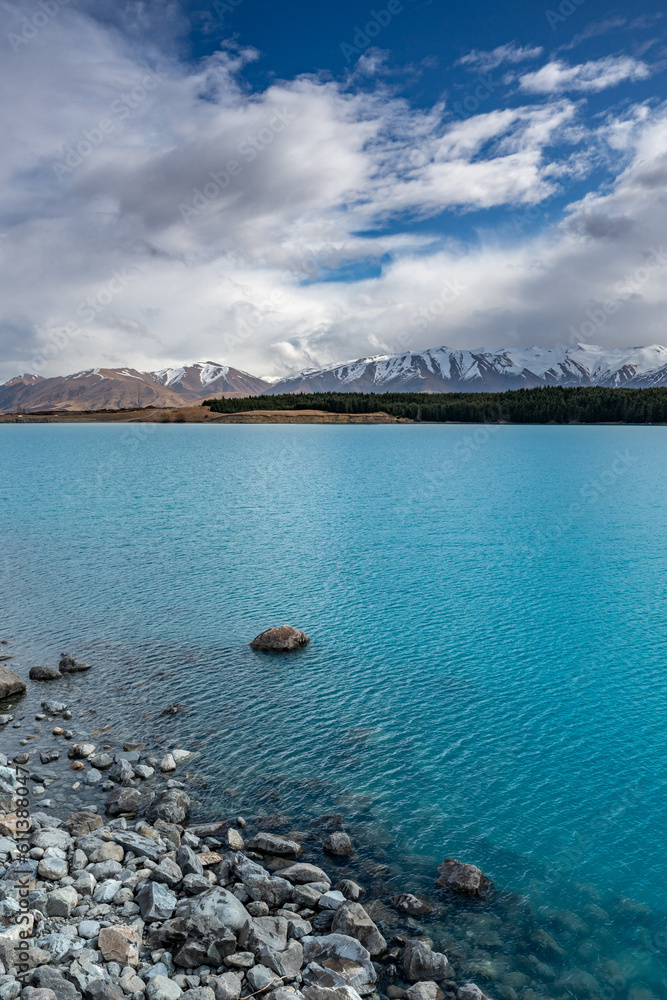 A scenic landscape of Aoraki Mount Cook background - Lake Pukaki with blue sky and clouds, South Island, New Zealand. View from Mt Cook Alpine Salmon Shop.