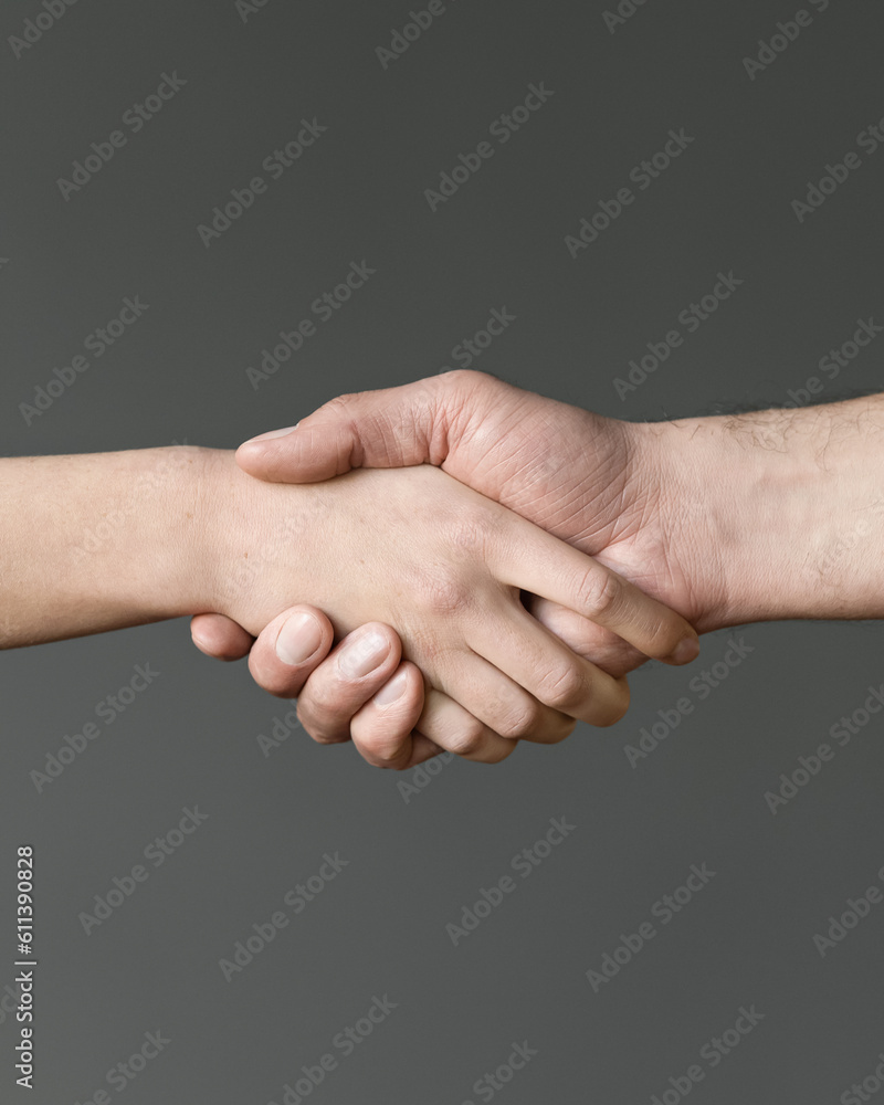 Handshake of man and woman. Two hands on gray background. Close-up. High quality photo Handshake of man and woman. Two hands on gray background. Close-up. High quality photo