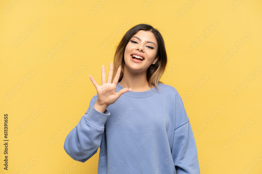 Young Russian girl isolated on yellow background counting five with fingers Young Russian girl isolated on yellow background counting five with fingers