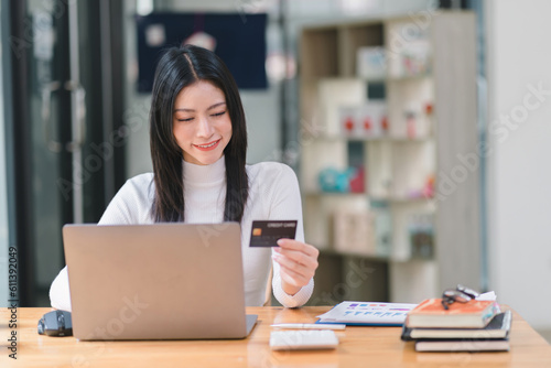 A woman making an online purchase on a computer using a mockup credit card.