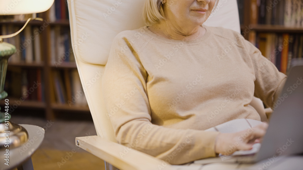 Close-up of a senior woman browsing the internet on her laptop, sitting in her home study
