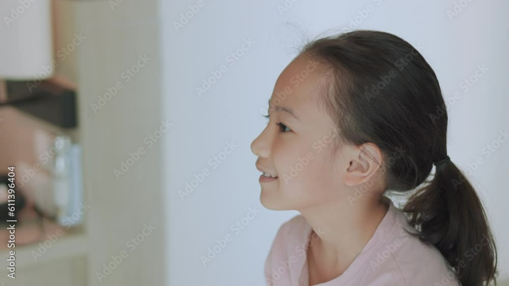 Face close up of adorable and cute girl who express her positive emotion through her beautiful smile in casual style with bright sunlight in the room shows concept of baby cam and child blogger.