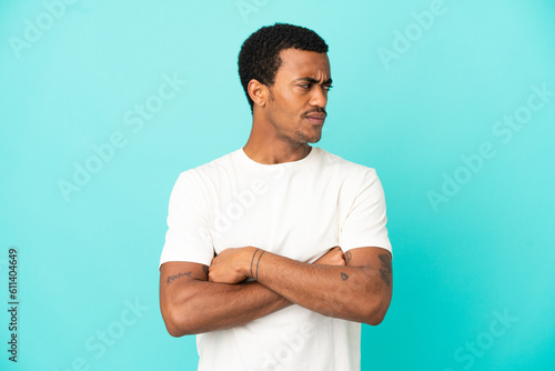 African American handsome man on isolated blue background keeping the arms crossed © luismolinero