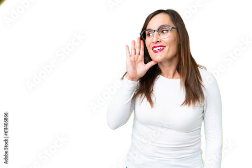 Middle age woman over isolated chroma key background listening to something by putting hand on the ear