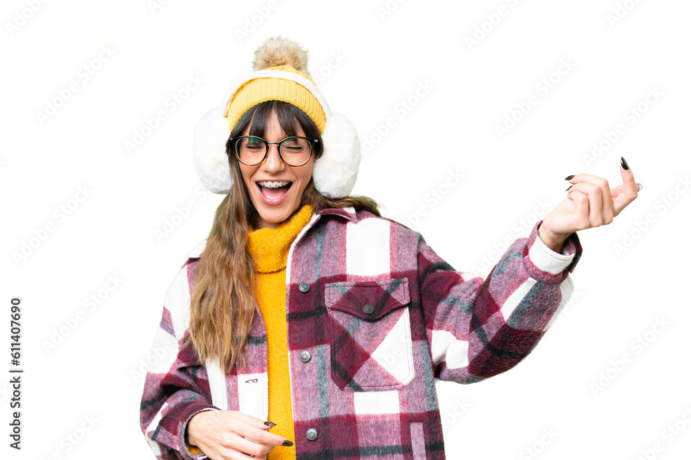Young caucasian woman wearing winter muffs over isolated chroma key background making guitar gesture Young caucasian woman wearing winter muffs over isolated chroma key background making guitar gesture