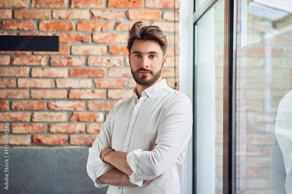Portrait of young businessman standing in small office looking at camera Portrait of young businessman standing in small office looking at camera
