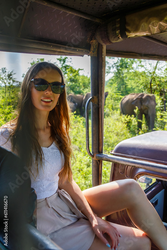 Photography A woman on safari in Udawalawe National Park, Sri Lanka, with Ceylon elephants i
