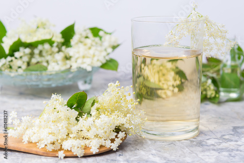 Homemade elderflower drink with sugar and lemon in a glass, light background