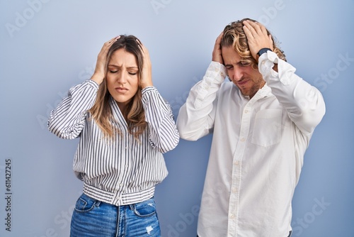 Fotografie Young couple standing over blue background suffering from headache desperate and stressed because pain and migraine