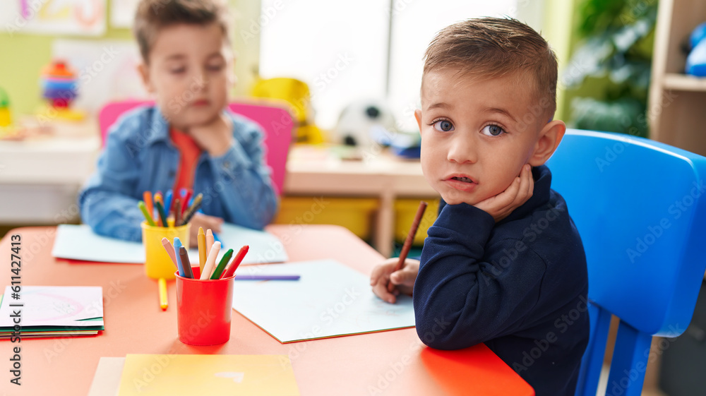Adorable boys preschool students sitting on table drawing on paper at kindergarten Adorable boys preschool students sitting on table drawing on paper at kindergarten