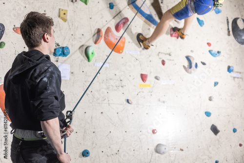 Young man ceratin climber on the climb wall center, sport activity concept