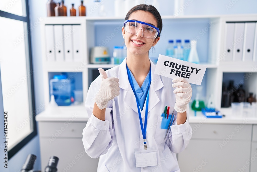Young beautiful woman working on cruelty free laboratory smiling happy and positive, thumb up doing excellent and approval sign